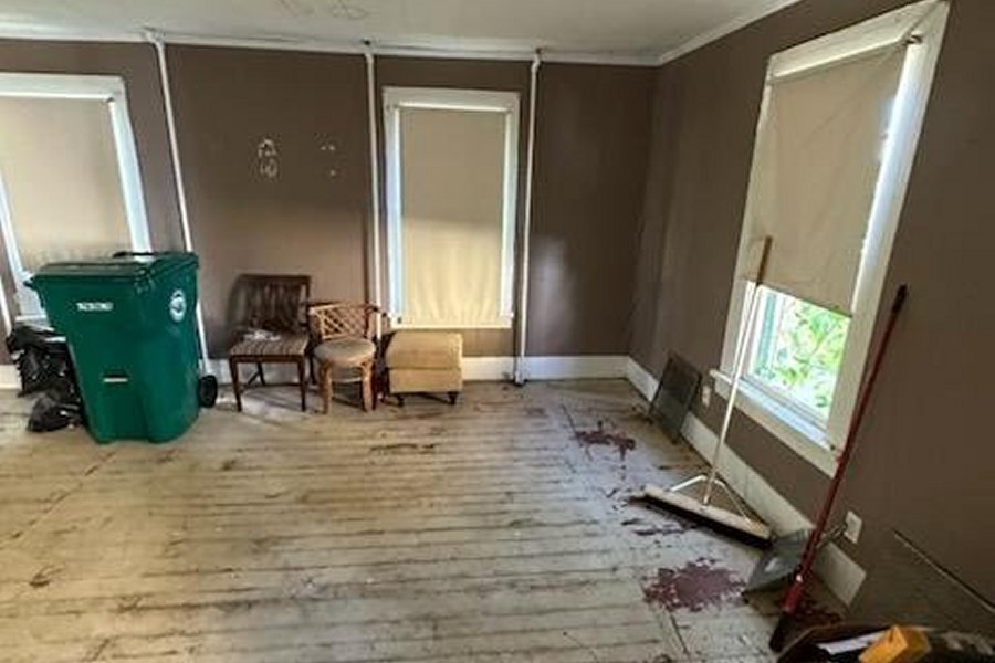 Tenant-damaged rental unit interior in Buffalo NY — holes in plaster walls and damaged flooring typical of bad tenant situations NCB purchases as-is
