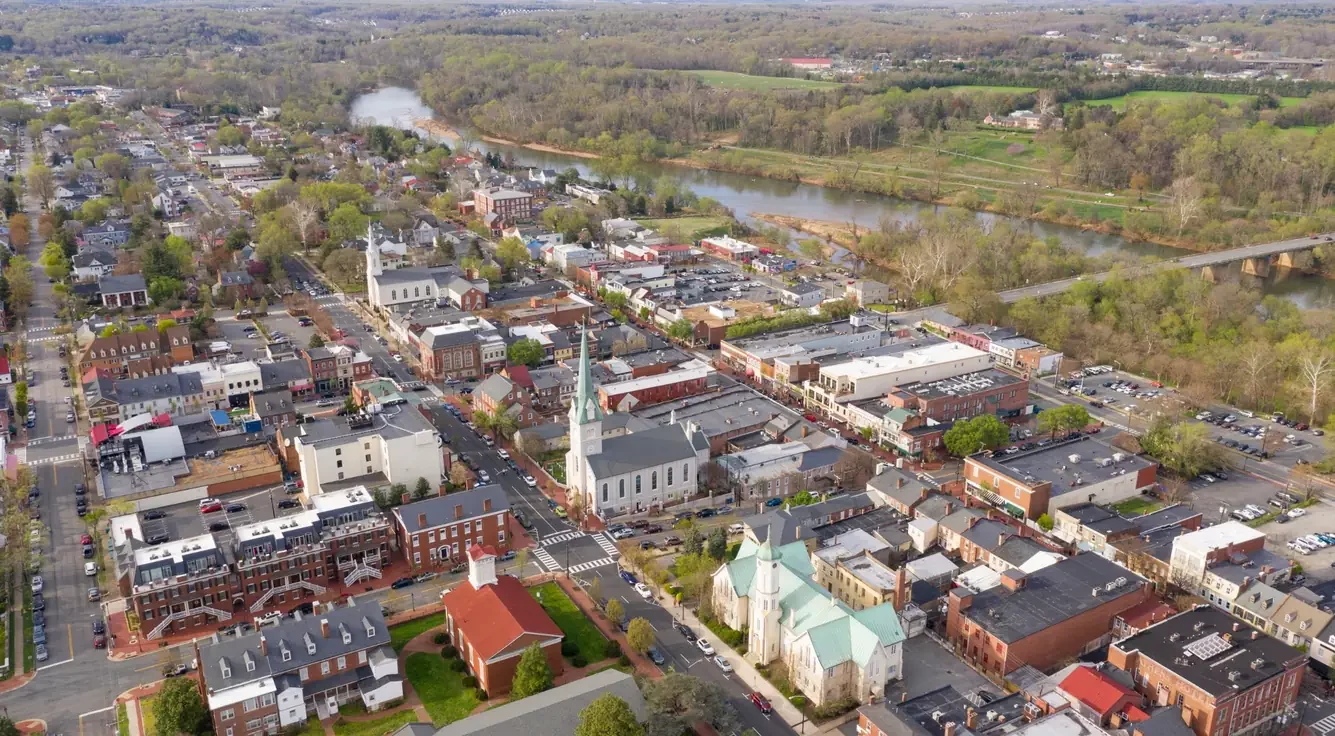 Aerial view of downtown Fredericksburg Virginia with historic buildings, Rappahannock River, and surrounding neighborhoods.